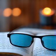Stylish blue light blocking glasses resting on a book in a softly lit room, symbolizing eye protection and better sleep.