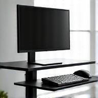 A sleek ergonomic standing desk converter with a monitor and keyboard, demonstrating adjustable height in a modern office.