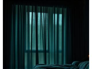 A dark bedroom with blackout curtains, no light, emphasizing darkness for sleep.